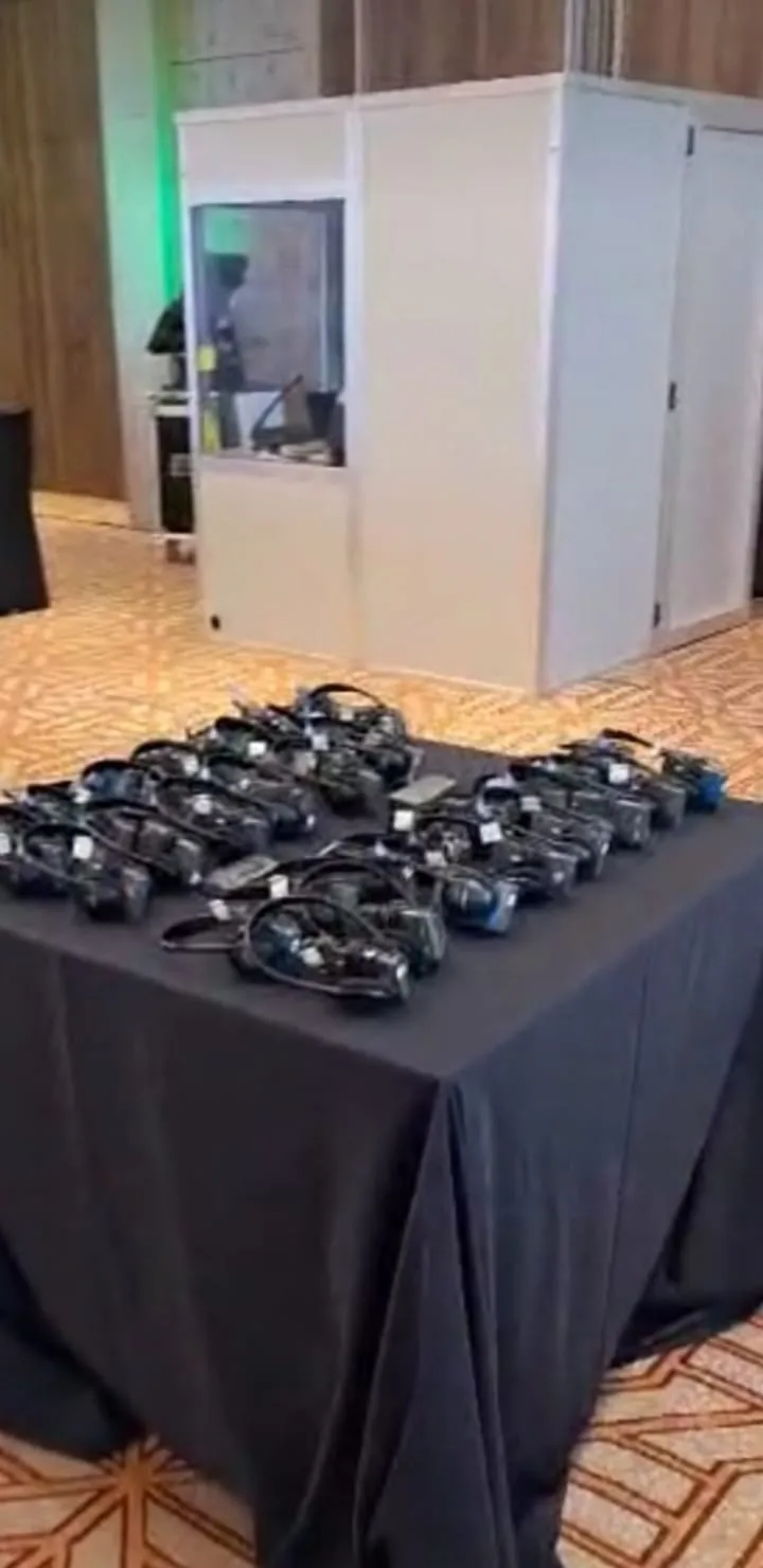 Récepteurs et casques alignés sur la table de distribution, devant la cabine d'interprétation